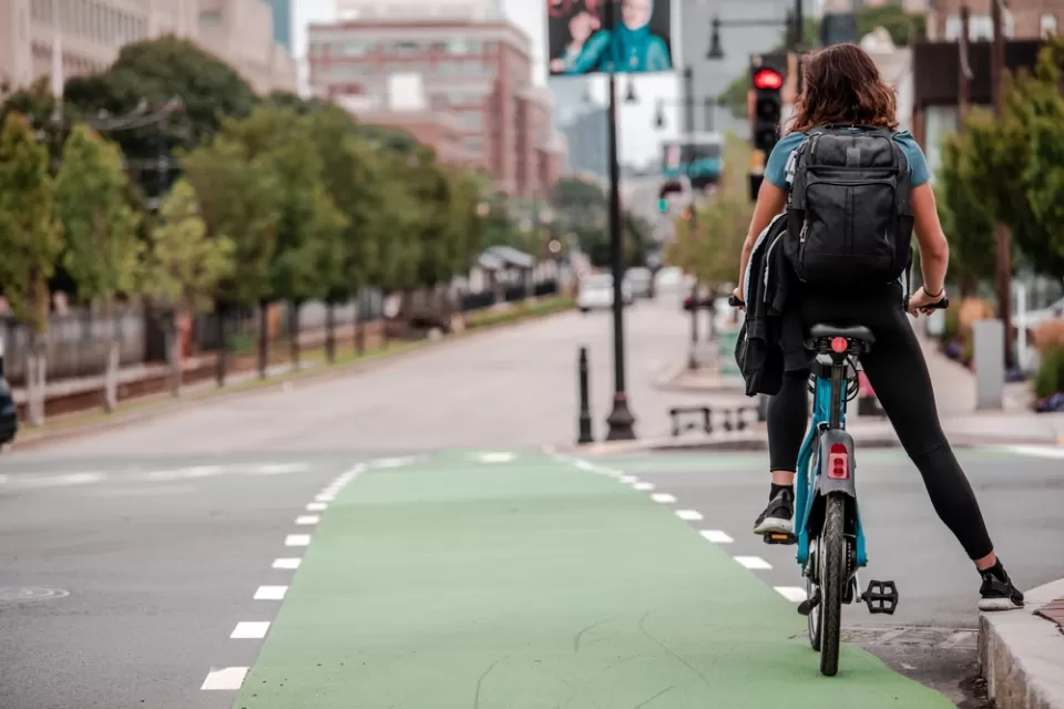 A person on a bike waits at an intersection by leaning against the curb.